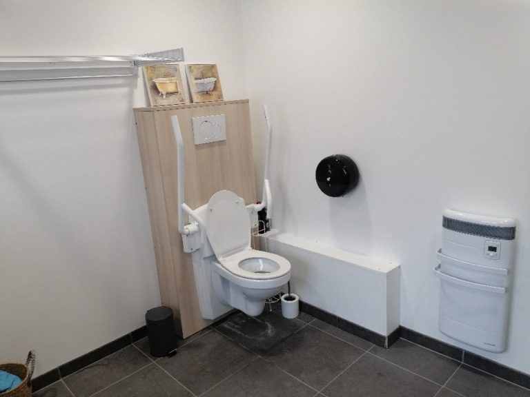 La salle de bain : Toilettes vastes pour les personnes à mobilité réduite. La douche à l’italienne permettant un accès facile au fauteuil roulant.  Sol anti-dérapant, Salle de bains équipée d’une machine à laver, une table à repasser, une centrale vapeur, des produits d’hygiène nécessaires à l’accomplissement de la toilette.