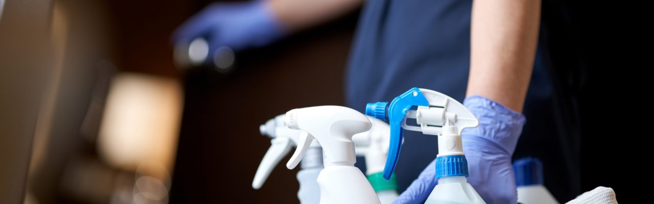 Cropped photo of chambermaid keeping all necessary cleaning and disinfection accessories in hotel room. Hotel service concept