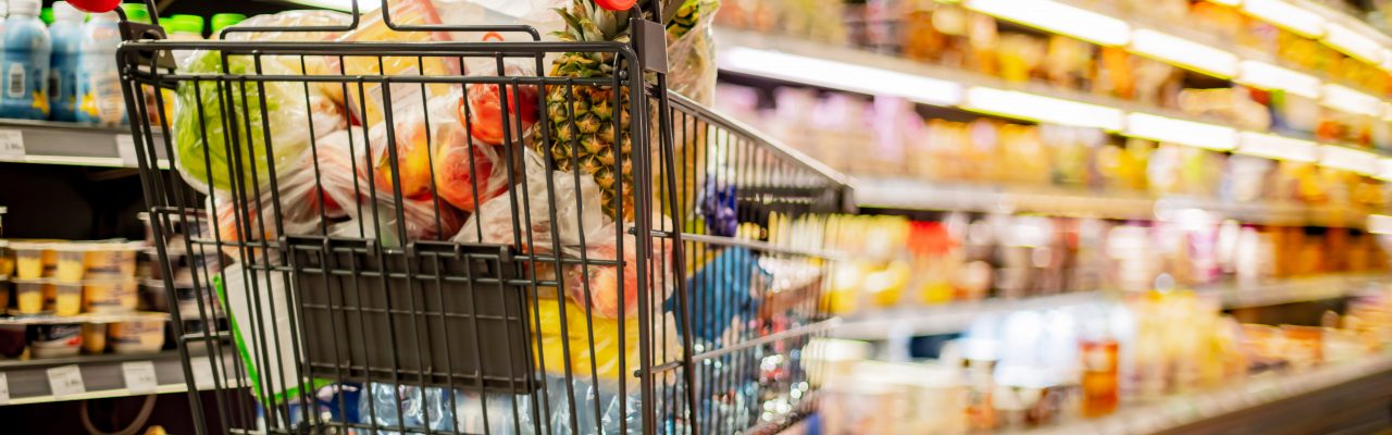 A shopping cart with grocery products in a supermarket